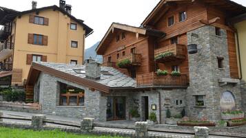A hotel with a stone facade, wooden balconies, and a sign indicating a restaurant.