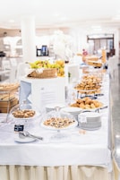 Mesa de buffet com diversos alimentos e uma placa indicando uma seção sem glúten.
