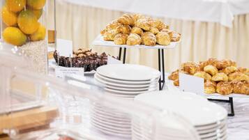 Ein Buffet mit verschiedenen Speisen, darunter Backwaren und Fleisch, präsentiert auf Tischen.