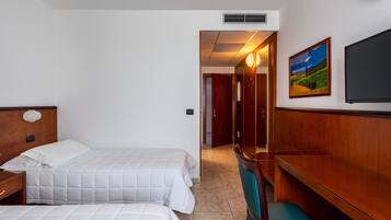A hotel room with two beds, a wooden bench, a TV, and a painting on the wall.