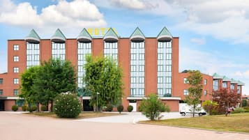 A hotel with a red brick facade, multiple windows, and a green roof.