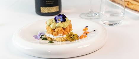 Une table à manger avec une bouteille de vin, un verre de vin blanc et une assiette de nourriture.