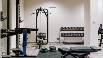 A gym with weightlifting equipment, a bench, and a rack of dumbbells.