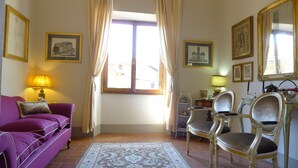Ein Wohnzimmer mit einem violetten Sofa, einem gemusterten Teppich und einem Fenster mit Vorhängen.