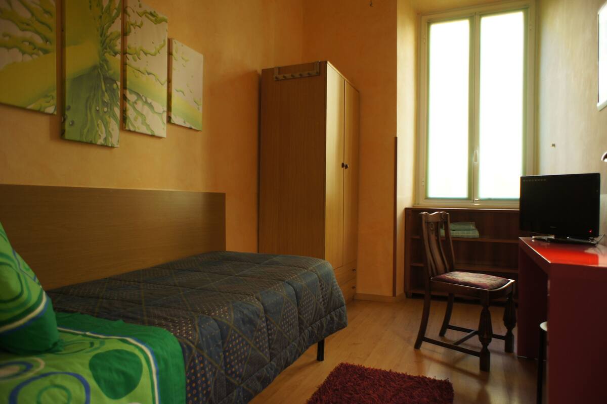 Una camera da letto con un letto, una scrivania, una sedia e una televisione.