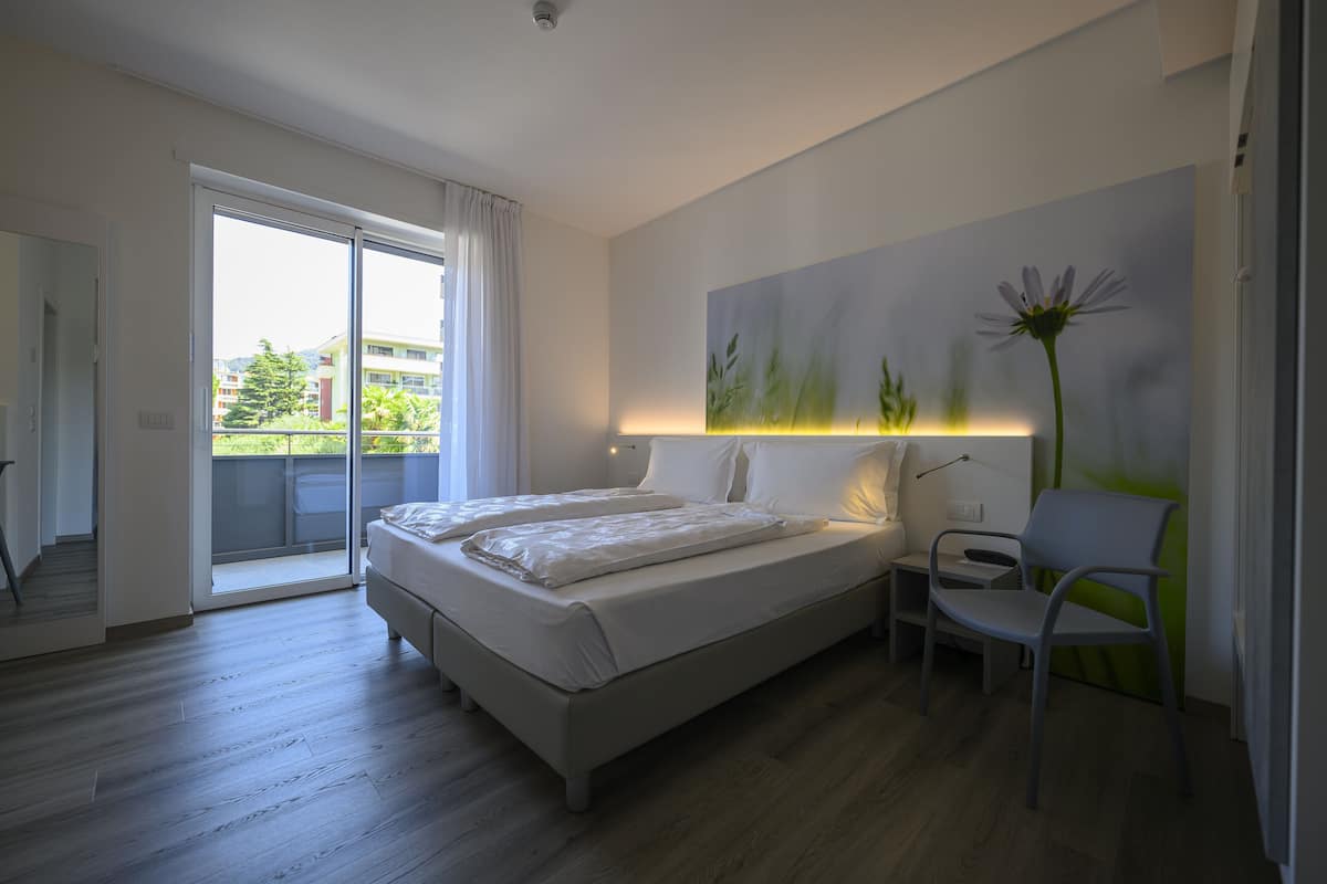 Un dormitorio con cama, una silla y un cuadro en la pared.