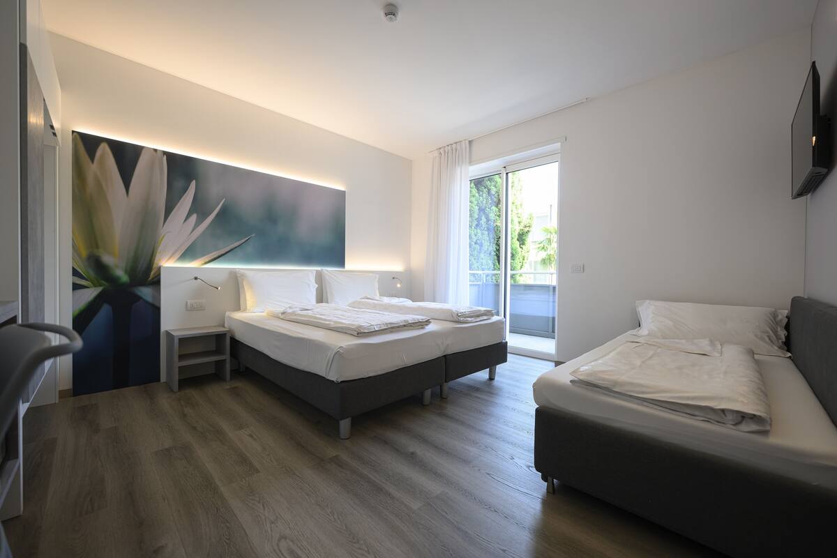 Una habitación de hotel moderna con cama, sofá, escritorio y un amplio ventanal.
