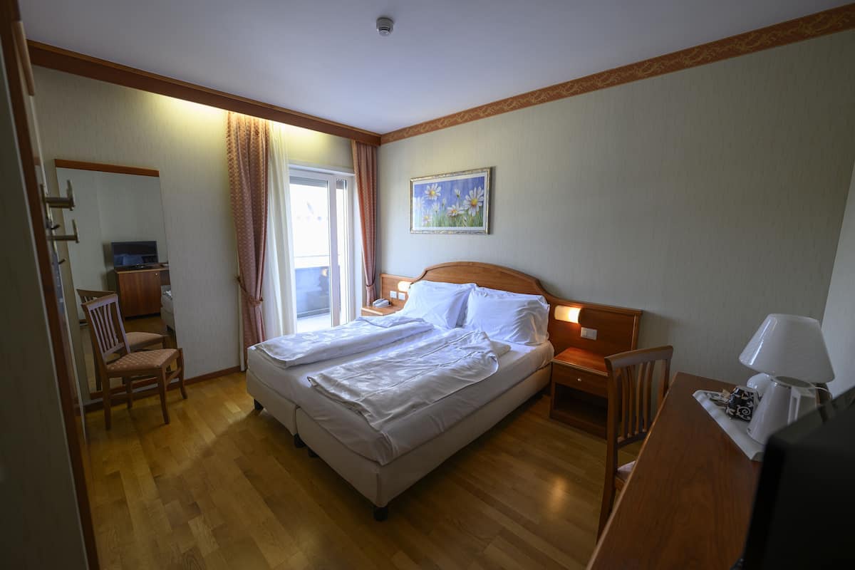 Habitación de hotel con cama, escritorio, silla, televisión y un cuadro en la pared.