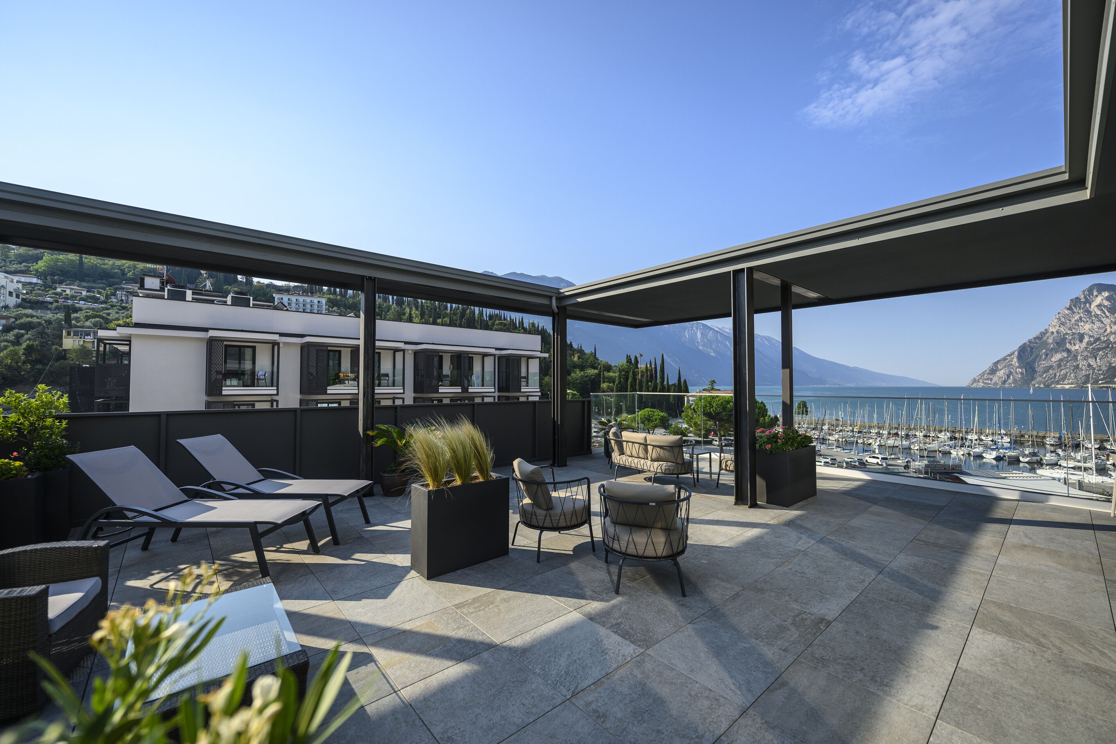 Terraço no telhado com área de estar ao ar livre, vista para o mar e uma montanha ao fundo.