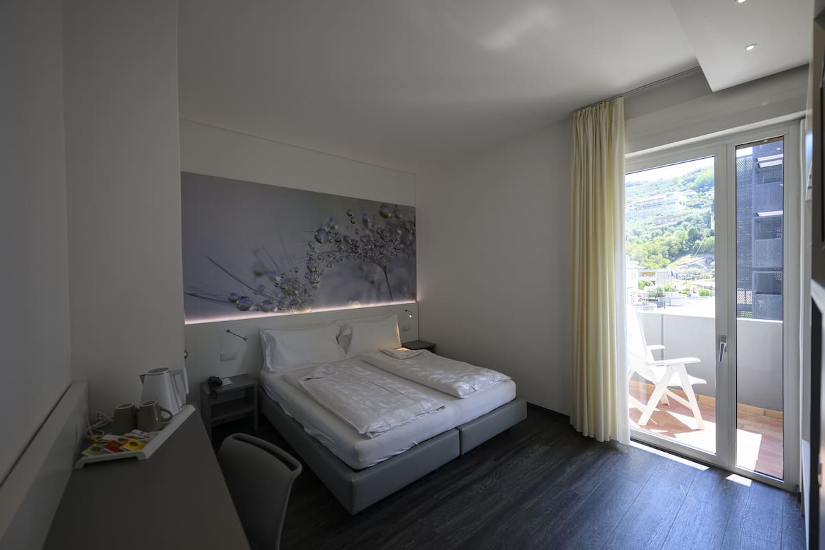 Una habitación de hotel moderna con una cama, un escritorio y vistas al exterior.