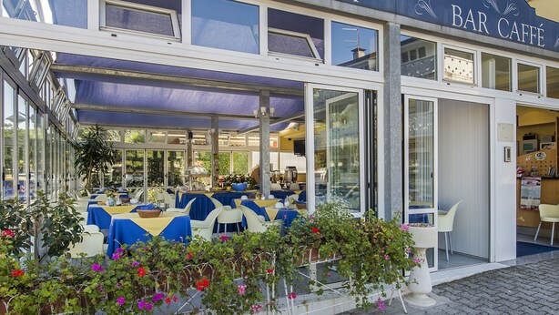 A hotel exterior with a bar and outdoor seating area. - Hotel Minerva (Lignano Sabbiadoro)