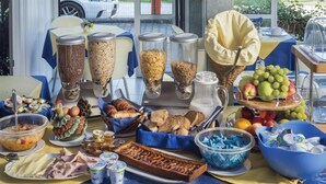 A buffet table with various food items and condiments, including fruits, bread, and beverages. - Hotel Minerva (Lignano Sabbiadoro)