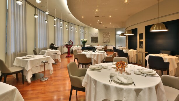A restaurant with round tables, chairs, and hanging pendant lights. - Palace Hotel Moderno (Pordenone)