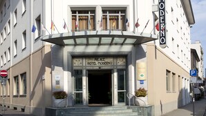The entrance to the Palace Hotel Moderno with a clear sign, steps leading up to the entrance, and multiple flags displayed outside. - Palace Hotel Moderno (Pordenone)