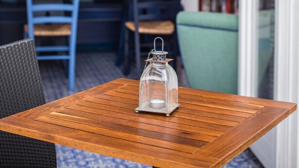 A wooden table with a glass lantern, a blue chair, and a bench in a room with a mirrored wall and shelves. - Mignon Meublè (Sorrento)