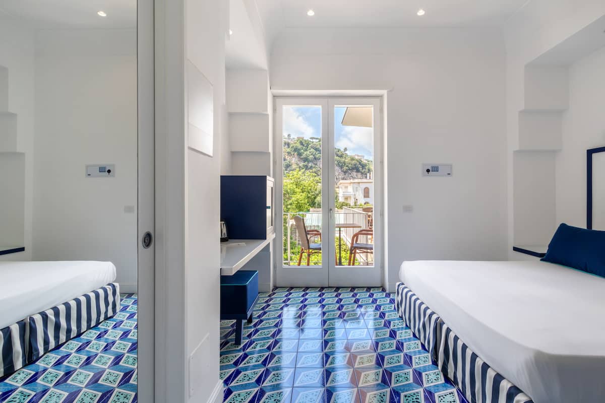 Habitación de hotel con dos camas, un escritorio y vistas al exterior.