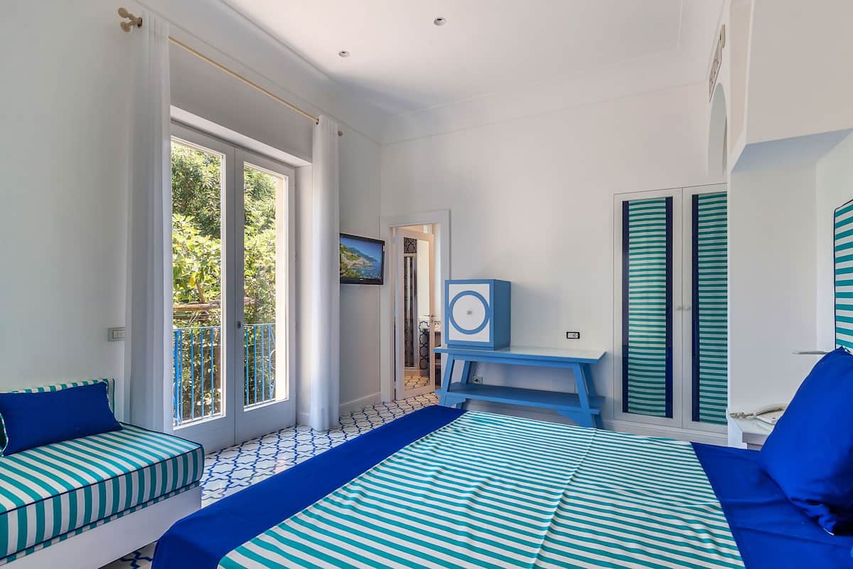 Una habitación con cama, escritorio y vista a zonas verdes.