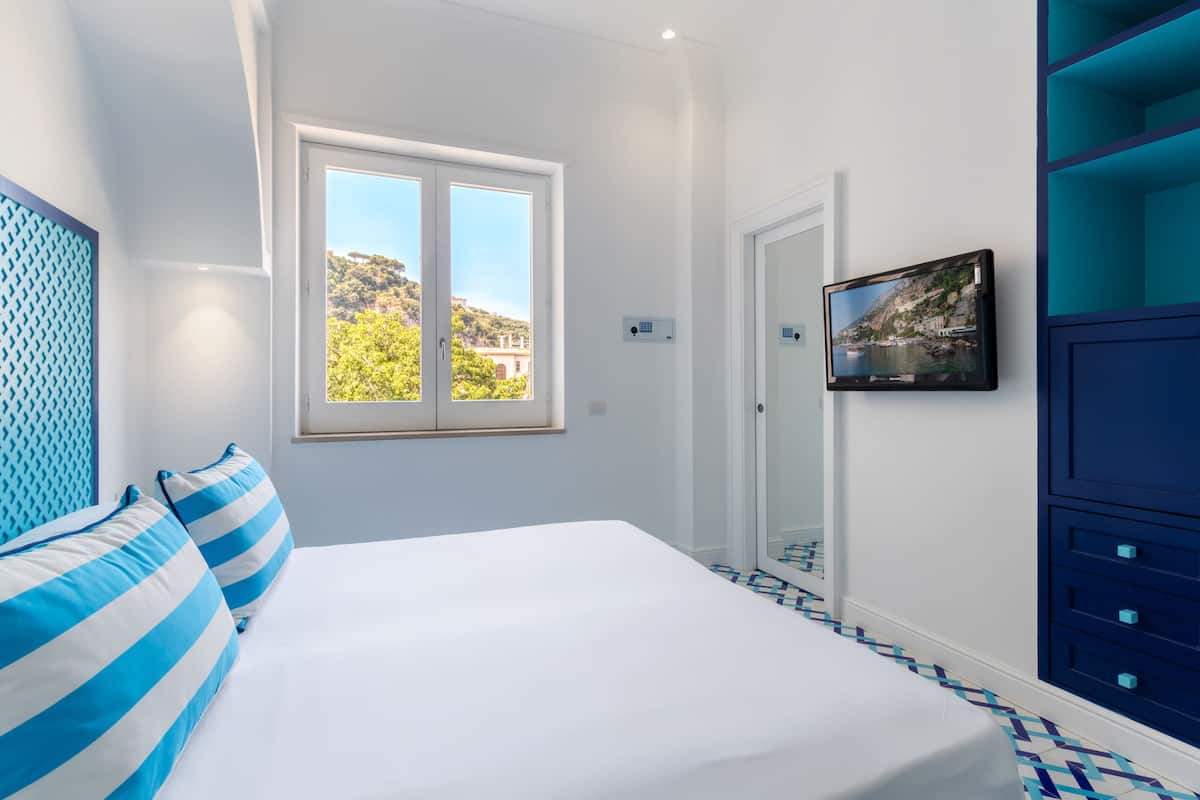 Un dormitorio con una cama, una ventana, un televisor y un armario azul.