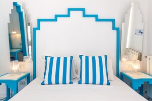 Una habitación de hotel moderna con una cama centrada entre dos mesitas de noche, cada una con una lámpara.