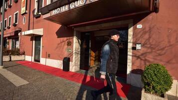 L'ingresso di un hotel con una moquette rossa e un cartello che recita 'HOTEL QUO VADO'.