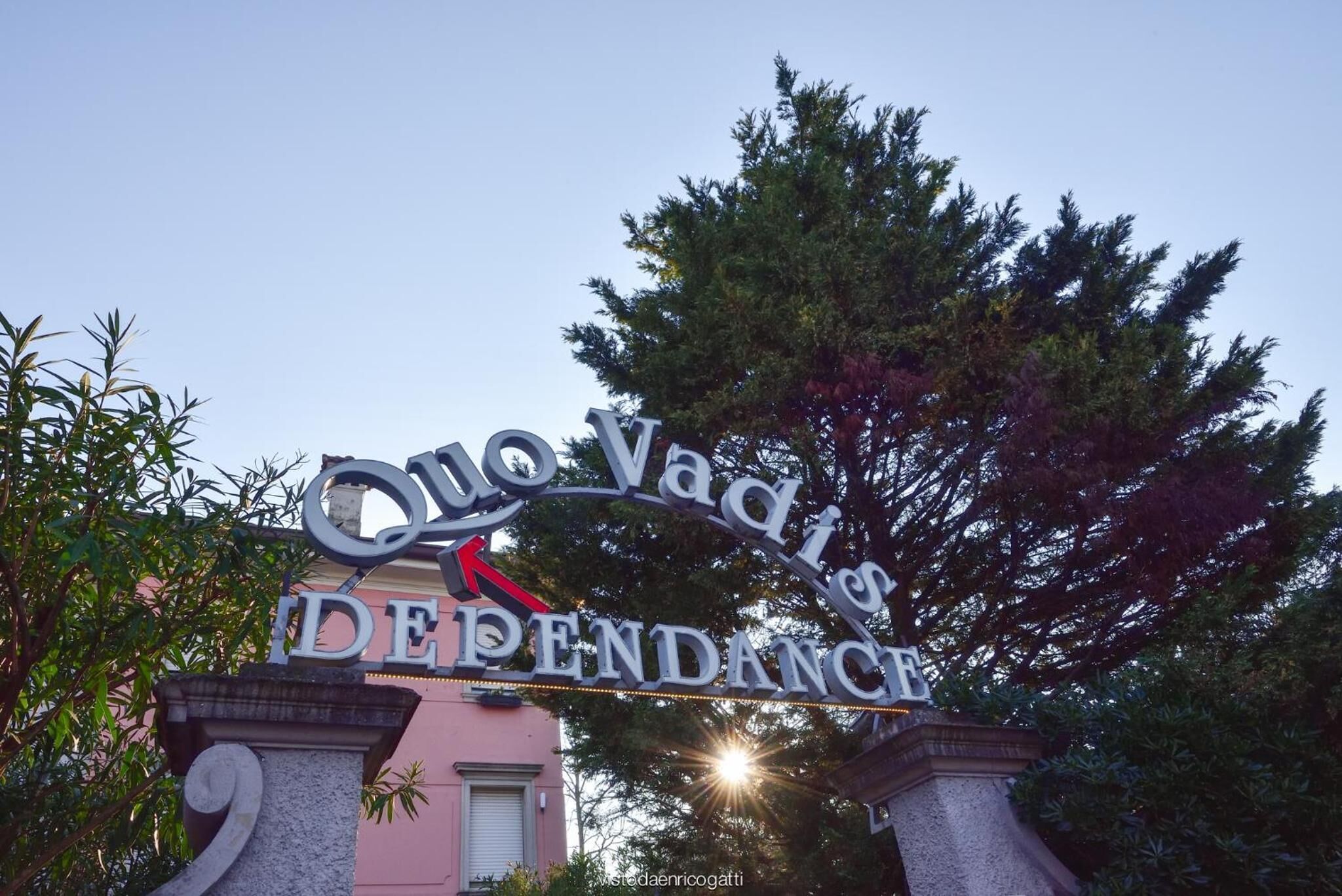 En skylt med texten ”Ono Vadis beroende” i ett stiliserat typsnitt, monterad på en stenstruktur med en dekorativ båge.