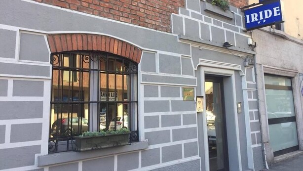 En bygning med butiksvindue, stor rude, metalgitter og en lille plantekasse med planter.