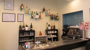 A bar area with shelves of liquor bottles, glasses, and a coffee machine. - Hotel Loreto (Milan)
