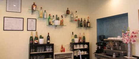 A bar area with shelves of liquor bottles, glasses, and a coffee machine.
