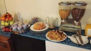 A buffet setup with various food items including fruits, yogurt, cookies, and a bundt cake. - Hotel Loreto (Milan)