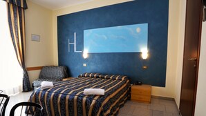 A hotel room with a large bed, a desk, and a chair. There is a painting on the wall and a window with curtains. - Hotel Loreto (Milan)