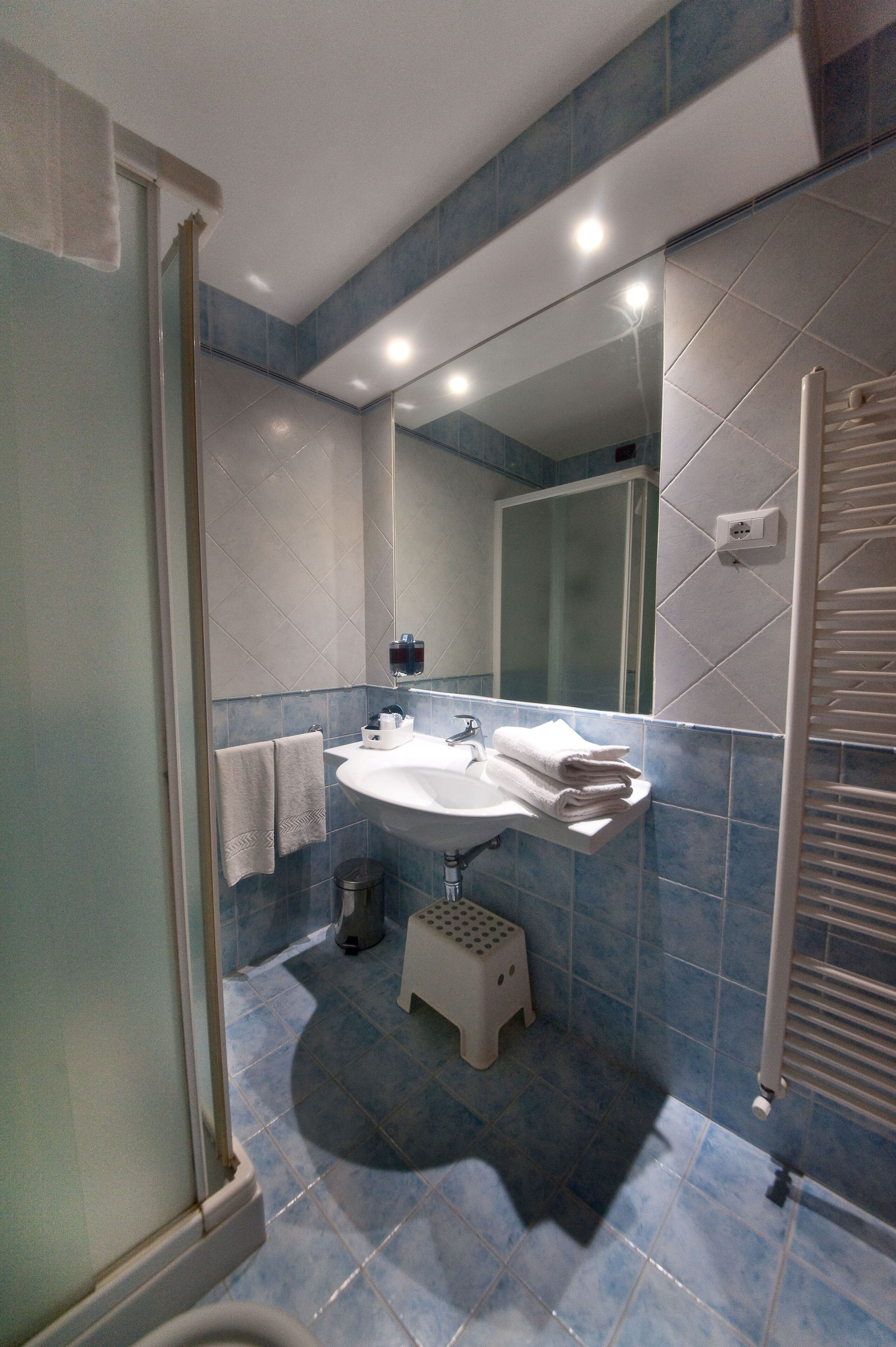 A bathroom with a sink, mirror, and shower.