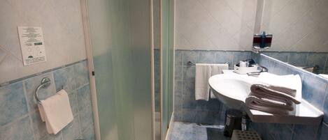 Un baño con ducha, bidé, lavabo e inodoro.