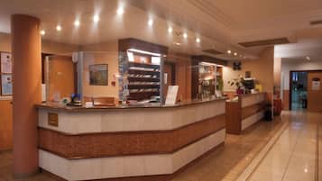 En hotellobby med en marmordisk, en klocka och en informationsbroschyr.