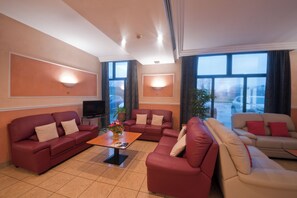 Ein Wohnzimmer mit zwei roten Sofas, einem beigen Sofa, einem Couchtisch und einem Fernseher.