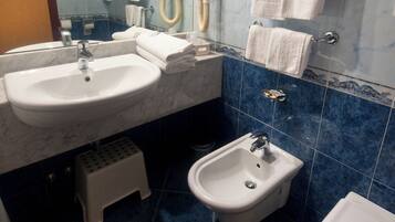 Une salle de bain avec deux lavabos, un bidet et des toilettes.