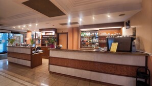 Een receptiebalie van een hotel, met een koffieapparaat en een selectie diverse dranken.
