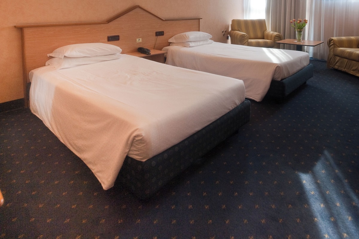 Una habitación de hotel con dos camas, una mesita, una silla y una mesita de noche.