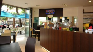 Un restaurante moderno con mostrador de madera, mesas al aire libre y una pantalla de televisión sobre el mostrador.