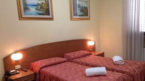 Un letto matrimoniale con una testiera in legno, due comodini con lampade e due quadri raffiguranti paesaggi appesi al muro.