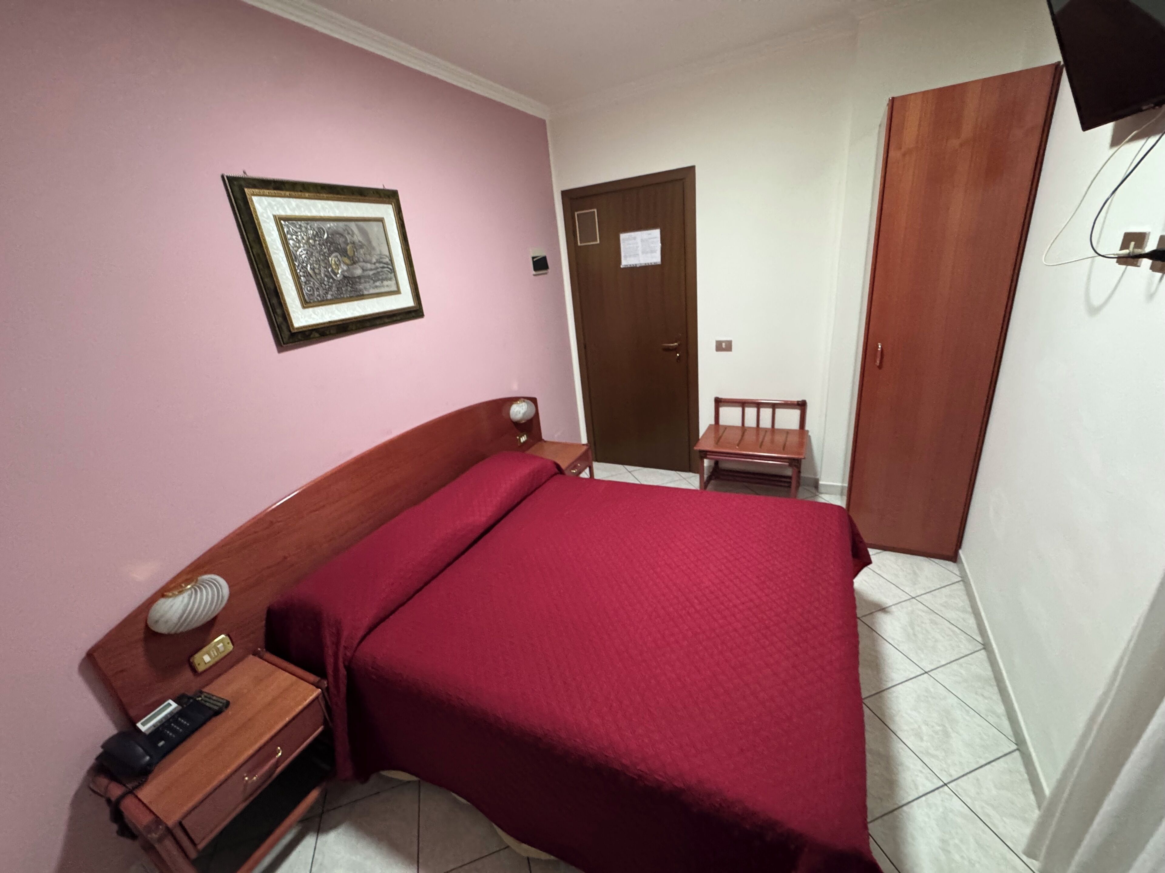 A bedroom with a bed, bedside table, and a chair.