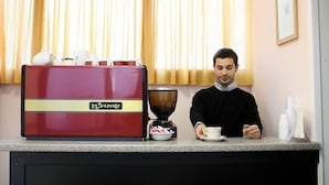 Una macchina da caffè e una persona che prepara un caffè al bancone.