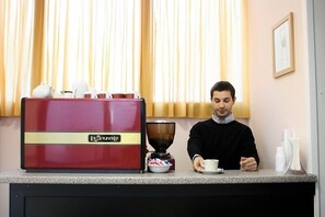 A coffee machine and a person preparing coffee at a counter. - Hotel La Caravella (Milan)