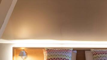 A neatly made bed with patterned pillows, a bedside lamp, and a wooden nightstand.