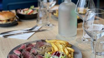 Una mesa de comedor con un plato de comida, copas de vino y una botella de agua.