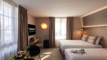 Habitación de hotel con dos camas, un escritorio, una silla, un televisor y una ventana con cortinas.