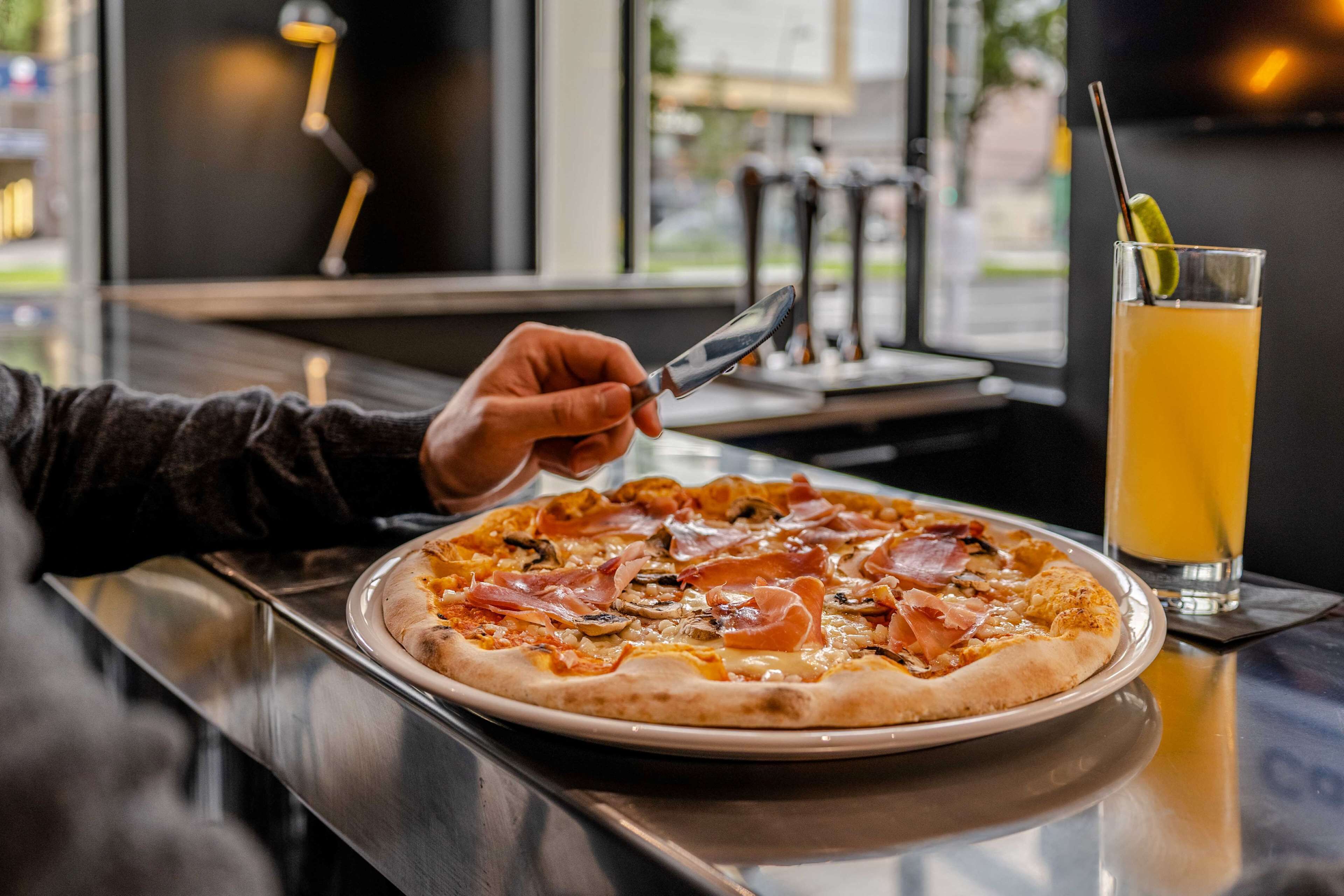 A pizza on a plate with a glass of orange juice beside it.
