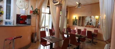 A restaurant with red chairs and tables, a coffee machine, and a counter with a menu.
