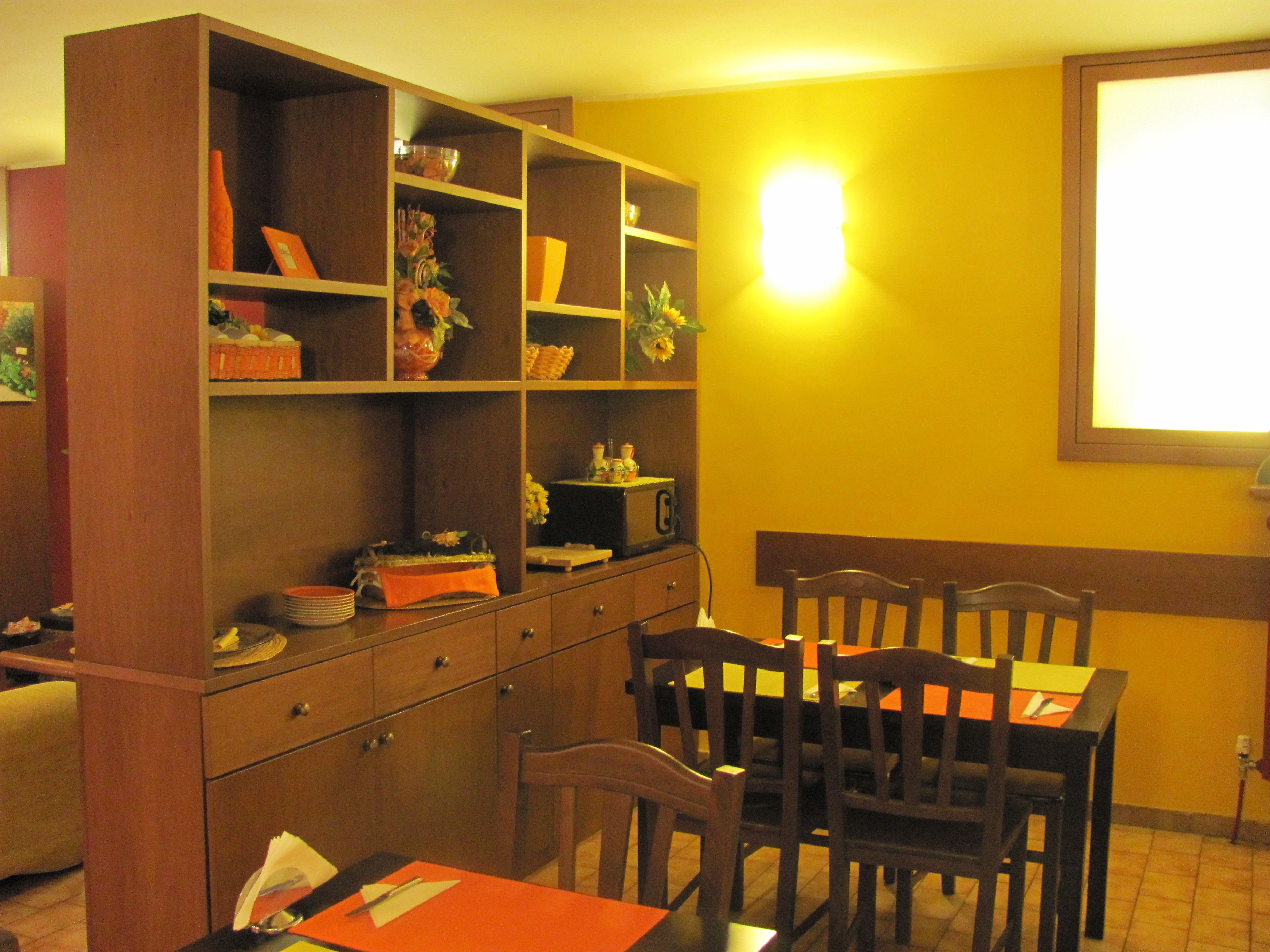 Un espace repas avec des meubles en bois, un buffet et un luminaire fixé au mur.