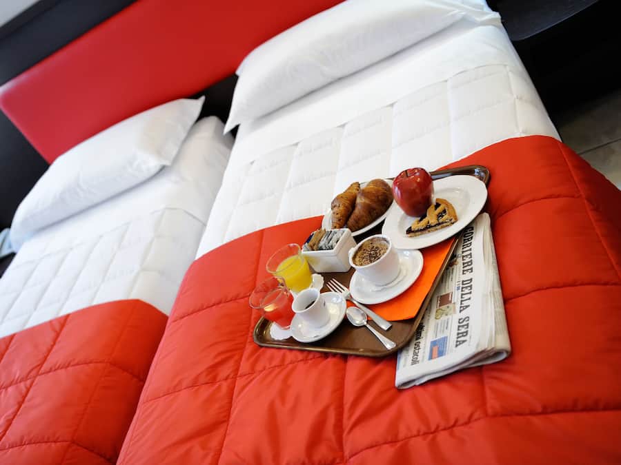 A bed with a tray of breakfast items including croissants, an apple, and orange juice.