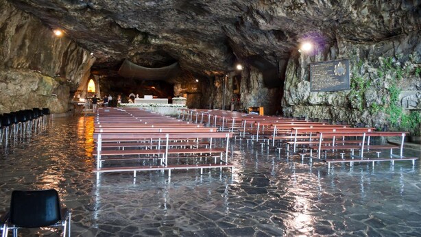 Un interior que recuerda a una cueva, con bancos y suelo de piedra.